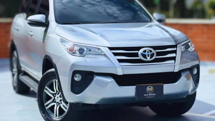 Toyota Fortuner plateada modelo reciente estacionada en terraza con fondo urbano
